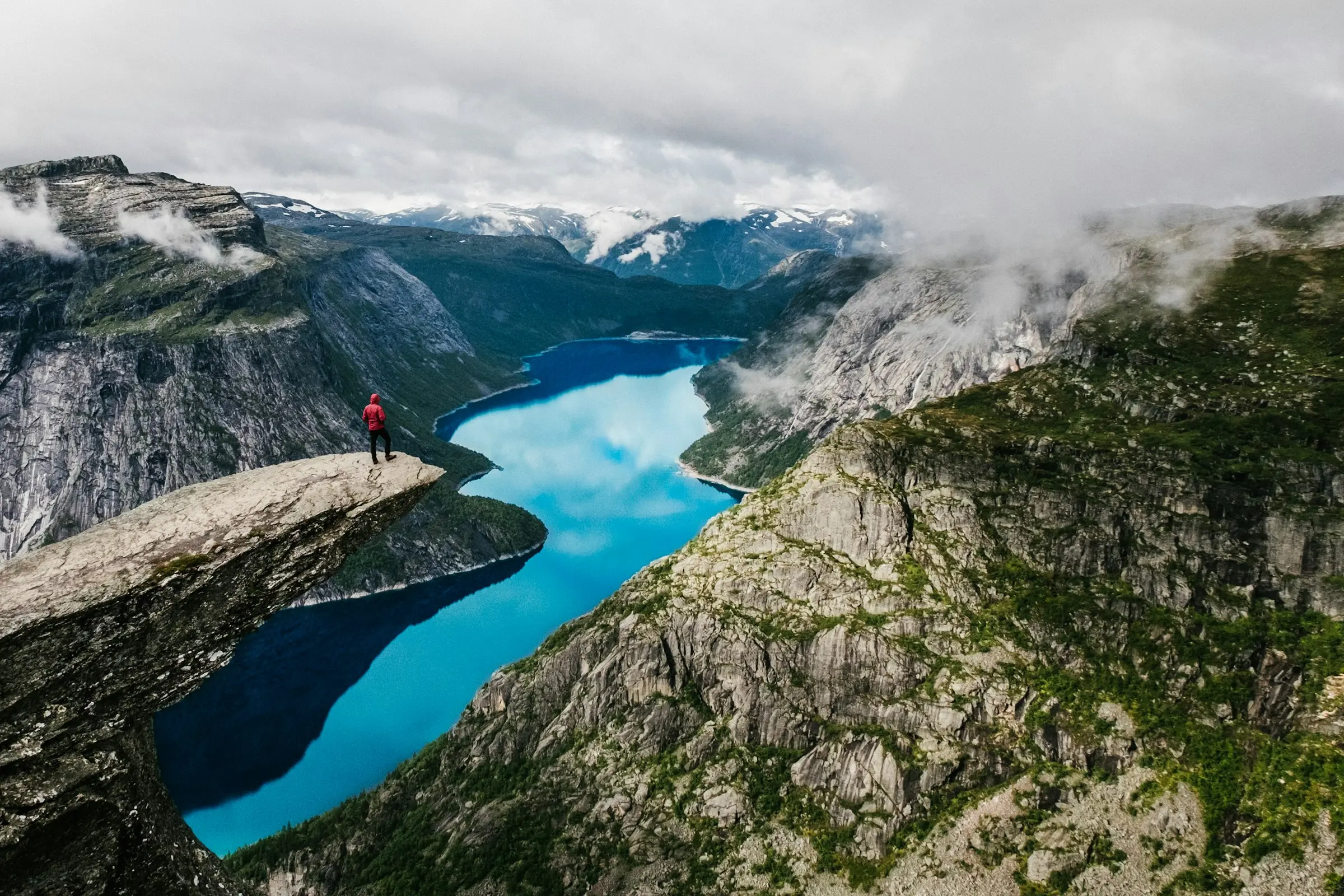 Hiker standing on the Trolltunga rock ledge above a fjord